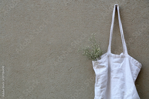 White reusable bag with gypsophila flowers, hanging on the wall. 