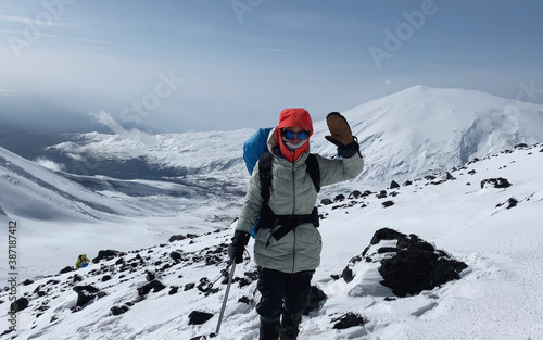 Female climber with an ice ax waving her hand affably. Mountain climbing.
