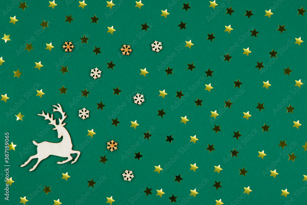 Top view of Christmas background made golden decorations, confetti, snowflakes and deer figure made of wood on green background. . Happy New Year greetings. Festive winter holidays backdrop. Flat lay Top view of Christmas background made golden decorations, confetti, snowflakes and deer figure made of wood on green background. . Happy New Year greetings. Festive winter holidays backdrop. Flat lay