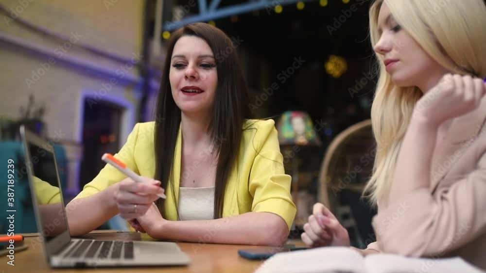 Two young mixed race women having a business meeting outside the office, in a street cafe setting
Two young mixed race women having a business meeting outside the office, in a street cafe setting
