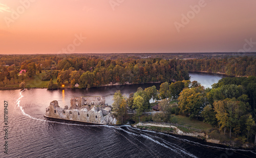 Aerial view of Koknese castle ruins at colorful sunset. Medieval ruins on the shore of river surrounded by forest. 