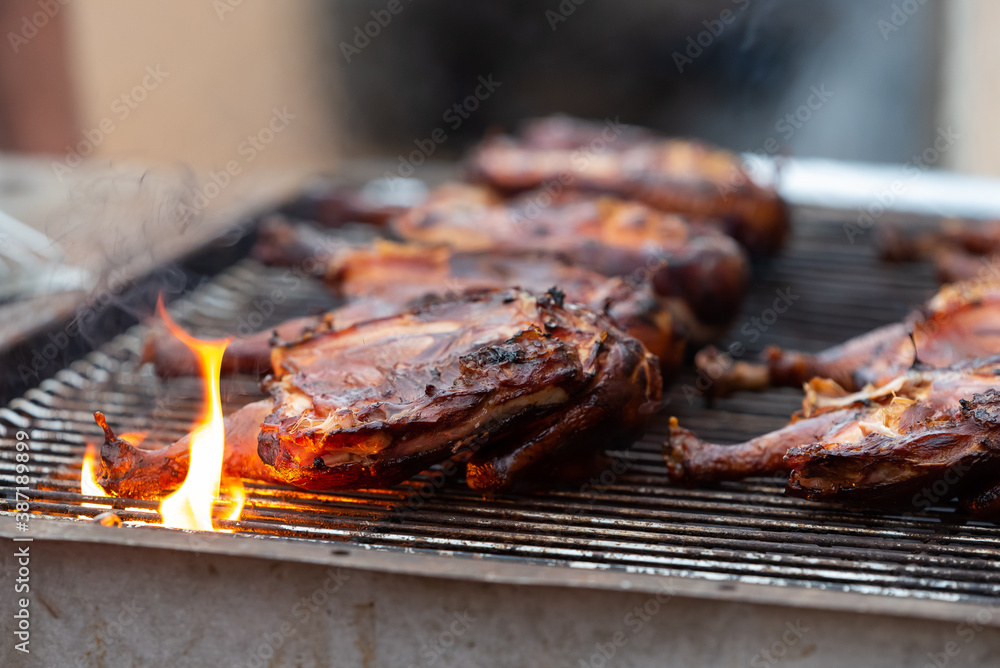 Chicken halves grilling on large commercial rotisserie. Meat being roasted on grates and flames for large barbeque gathering. Chicken halves grilling on large commercial rotisserie. Meat being roasted on grates and flames for large barbeque gathering.
