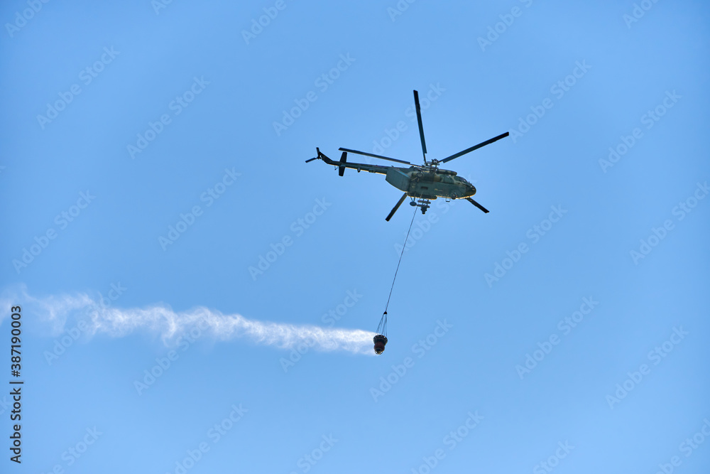 Fire fighting helicopter with water bucket on blue sky background Fire fighting helicopter with water bucket on blue sky background