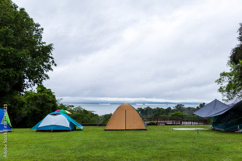 Tourist tents set up on the lawn near the river.