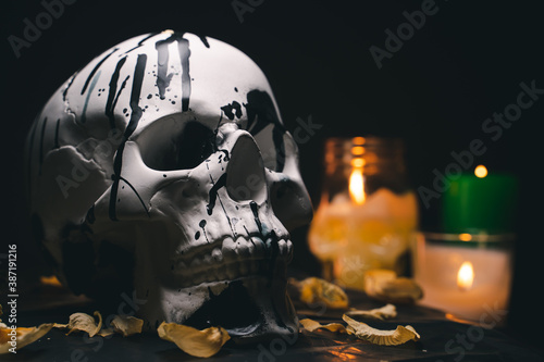 Decorative white human skull in a mysterious setting with burning candles
