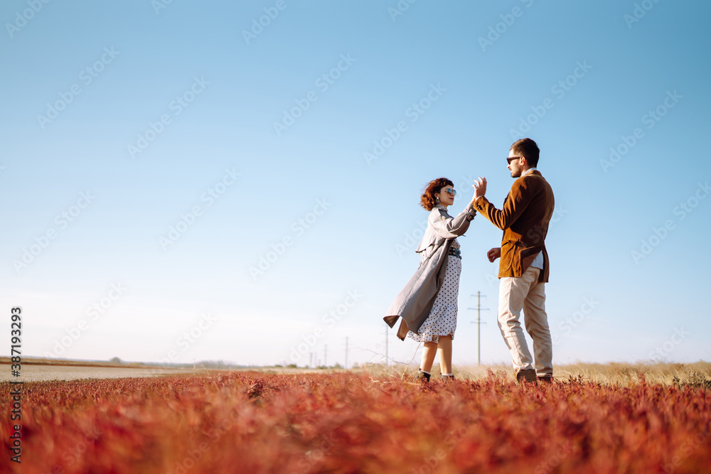 Young loving couple walking and hugging in autumn field. Enjoying time together. Fashion, lifestyle and autumn mood. Young loving couple walking and hugging in autumn field. Enjoying time together. Fashion, lifestyle and autumn mood.