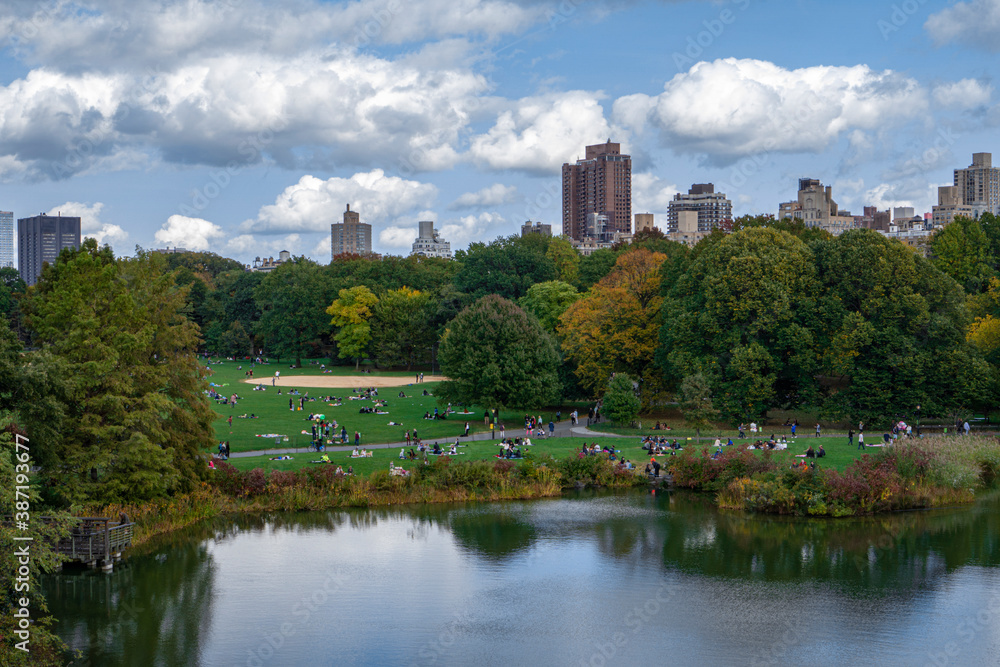 New York / USA - October 10 2020: Reflection in lake water of Central Park with a view of trees, people and buildings in the background New York / USA - October 10 2020: Reflection in lake water of Central Park with a view of trees, people and buildings in the background