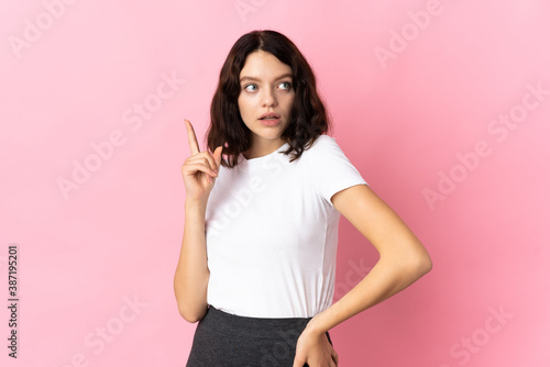Teenager Ukrainian girl isolated on pink background thinking an idea pointing the finger up