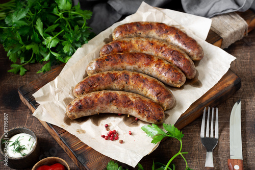 Fried sausages. Grilled sausages with spices on a wooden serving Board. Delicious meat sausages	
