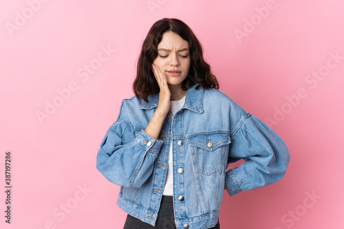 Teenager Ukrainian girl isolated on pink background with toothache © luismolinero