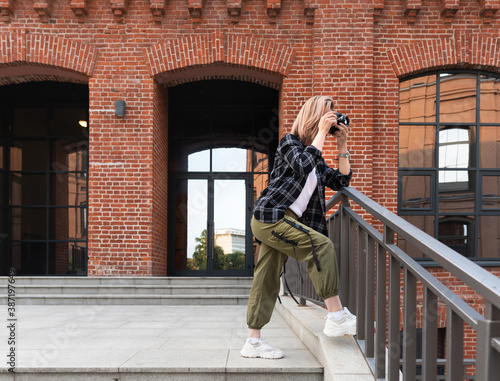 Photos Girl in cargo pants, white sneakers and flannel shirt taking a picture with came