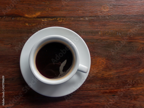 White coffee cup with black coffee placed on the wooden table