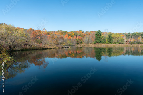Fall colored foliage reflects off of the far shoreline of a country lake