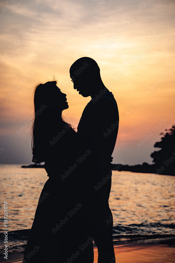 Silhouette of a loving couple on the sunset background.
