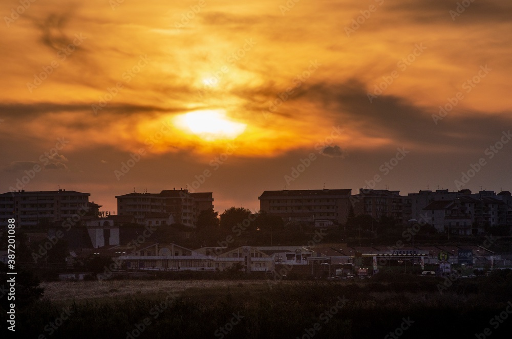 Fototapeta premium Urban panorama with sun at sunset