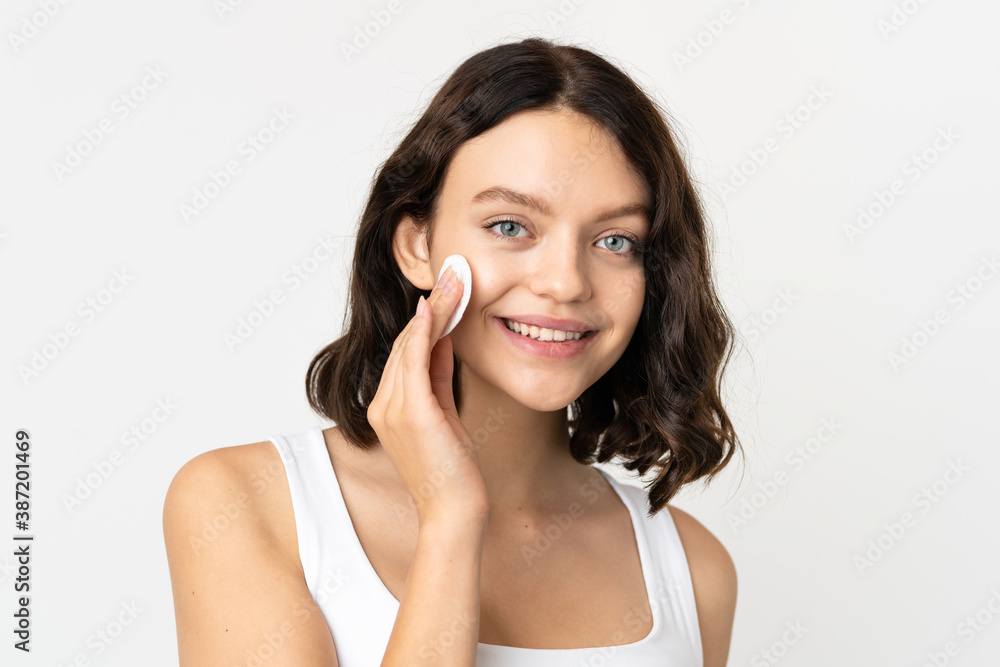 Teenager Ukrainian girl isolated on white background with cotton pad for removing makeup from her face Teenager Ukrainian girl isolated on white background with cotton pad for removing makeup from her face