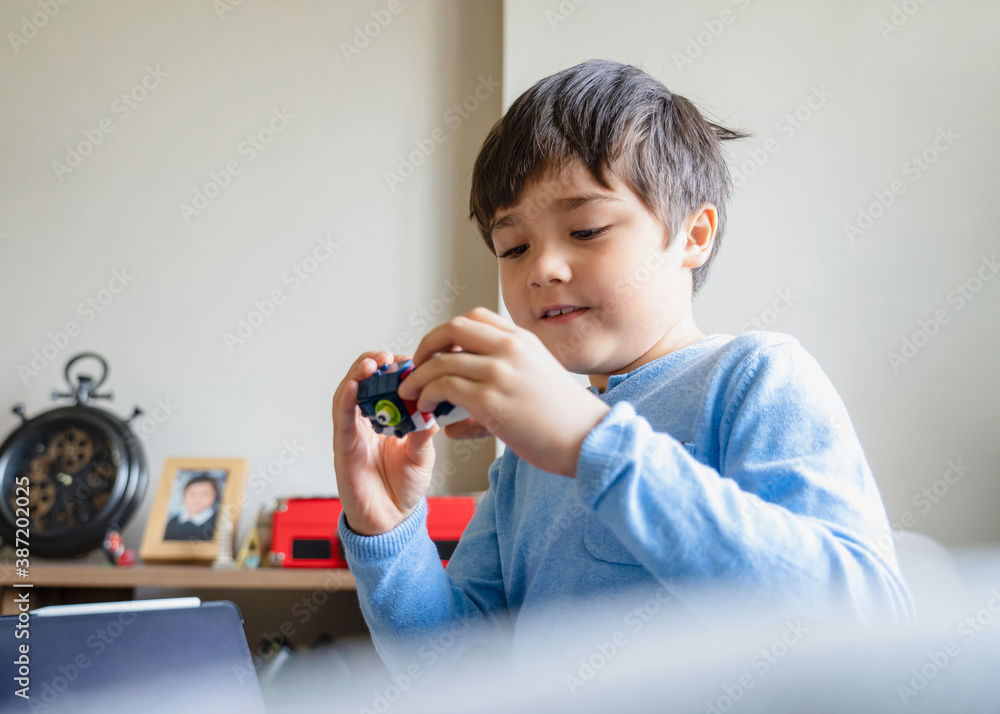 Portrait happy kid playing with colourful plastic toys alone in living room, New normal life style Child boy relaxing at home on weekend. Positive child, happiness and healthy of children concept Portrait happy kid playing with colourful plastic toys alone in living room, New normal life style Child boy relaxing at home on weekend. Positive child, happiness and healthy of children concept