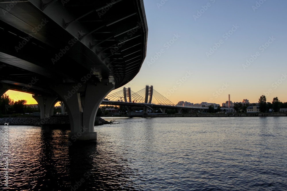 Silhouette of spans, motorway supports over the river and cable-stayed bridge with arched pylons Silhouette of spans, motorway supports over the river and cable-stayed bridge with arched pylons