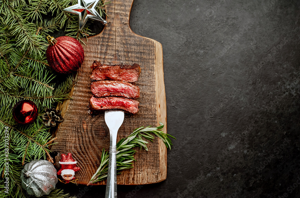 Different degrees of roasting of steak on a meat fork for Christmas on a background of a stone with a spruce and Christmas toys with copy space for your text Different degrees of roasting of steak on a meat fork for Christmas on a background of a stone with a spruce and Christmas toys with copy space for your text