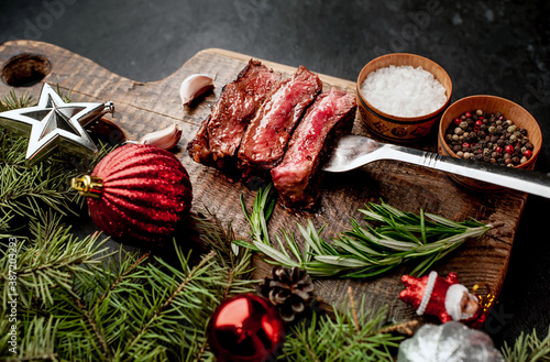 Different degrees of roasting of steak on a meat fork for Christmas on a background of a stone with a spruce and Christmas toys with copy space for your text