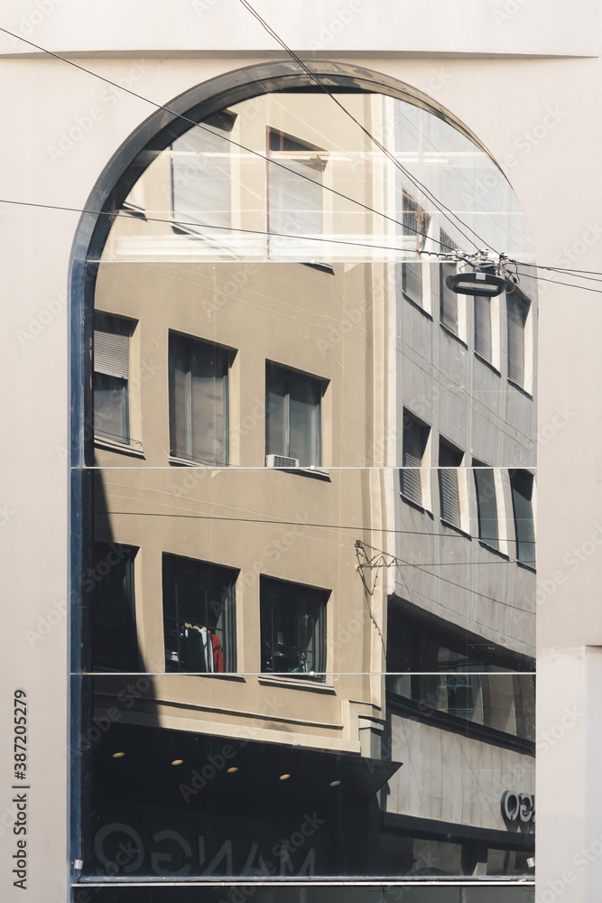 Abstract fragment of old building architecture reflected in modern corporate building. Front view of the building. Walls made of glass and concrete. Milan, Italy