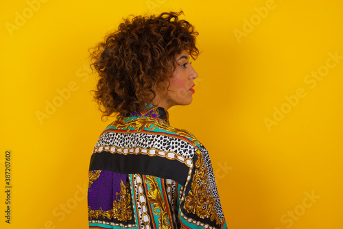 The back view of a girl with long straight wavy and shiny hair standing against gray wall. Studio Shoot.