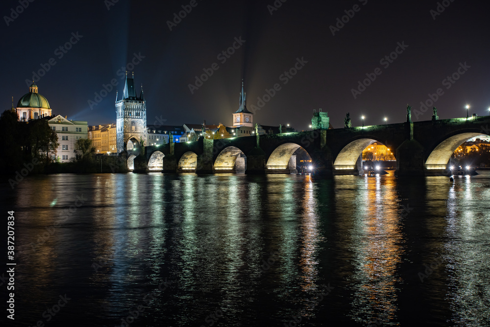
street lights and light from him on the Charles Bridge from the 14th century on the Vltava river and reflections of the world in the sky and the river