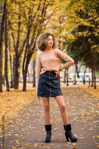 Portrait of a young beautiful girl in beige sweater and black skirt