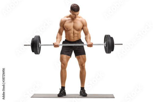 Full length portrait of a strong muscular guy lifting weights on an exercise mat