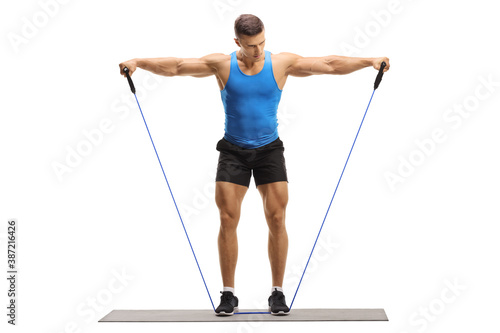 Obraz na płótnie Full length portrait of a muscular guy exercising with a resistance band