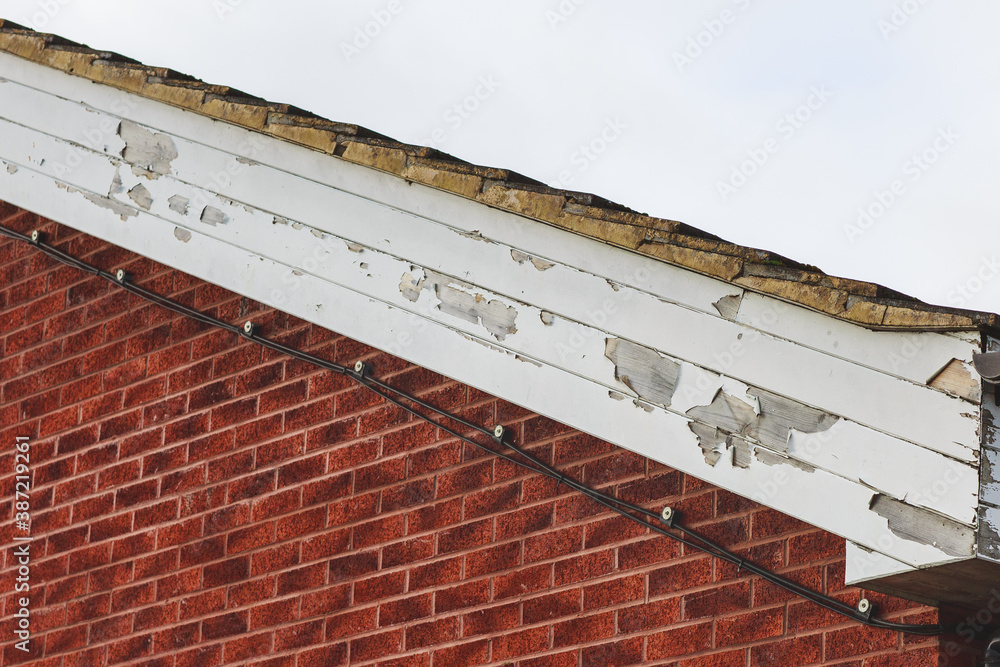 Flaking paint on wooden fascia boards to a side of a brick built building Stock Photo Adobe Stock