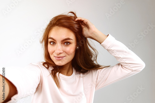 Young beautiful woman taking a selfie on a gray studio background