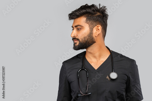 indian doctor or surgeon with stethoscope on gray background