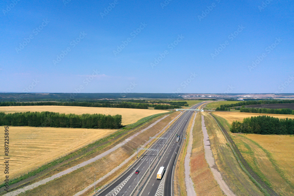 Aerial photography of agricultural fields in Russia. Beautiful views. Highway along the fields. Sunny day.