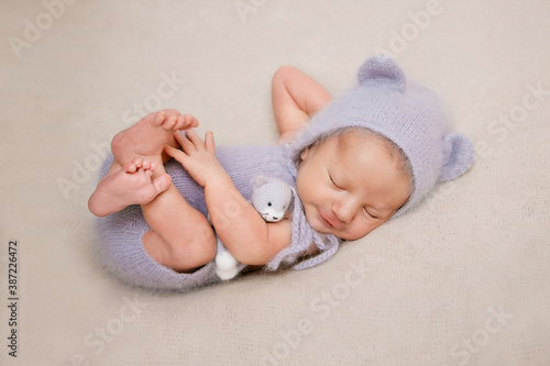 newborn boy dressed as a gray mouse sleeping with a toy