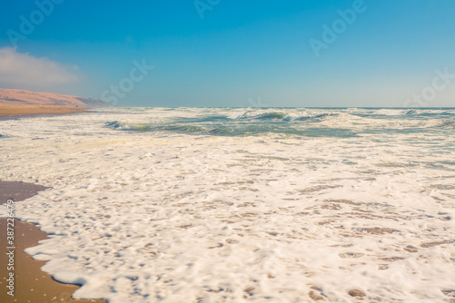 Abstract seascape background. Sandy beach  ocean waves  and clear blue sky on background