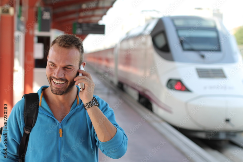 Blonde man calling by phone from train station Blonde man calling by phone from train station