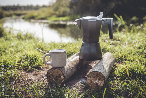 campfire coffee maker in nature near the river/picnic with a coffee maker on a campfire with cups of coffee on the background of the river 