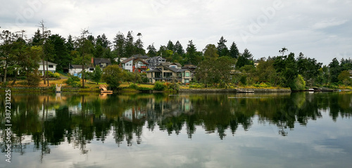 Houses at a lake with smooth reflection and forest in the background