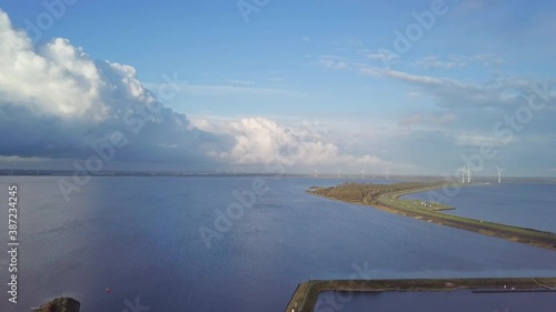 Drone flight at a sailboat port on the Grevelingen Sea in Zeeland. Evening sun with calm water, offshore wind gusts and great cloud formations. In the distance some wind turbines. Bruinisse Netherland photo