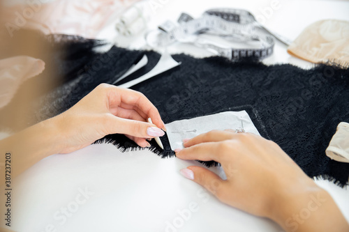 Woman tailor hands, scribbles sketch for sewing underwear on black lace with chalk