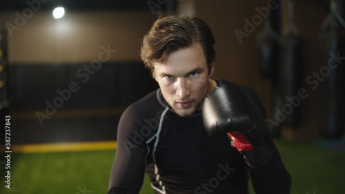 Aggressive athlete practicing boxing blows in sport club. Boxer training at gym