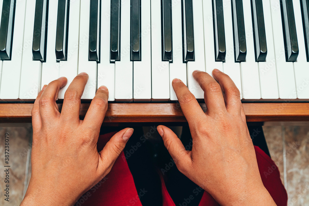 Naklejka premium Closeup woman's hand playing piano. Favorite classical music. Top view with dark vignette