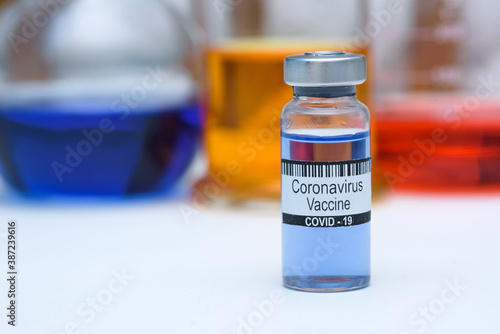Coronavirus vaccine in bottle for injection on table against background medical laboratory, space for text. Defeating SARS-CoV-2 coronavirus epidemic. Scientists have found vaccine against coronavirus
