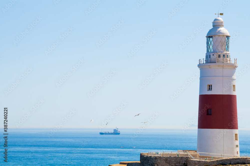 Landscape of a red and white lighthouse on a cliff with the ocean in the background