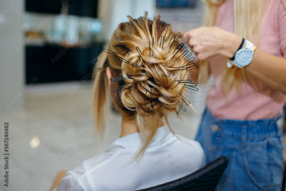 professional hairdresser makes young beautiful bride a wedding hairstyle in the morning before the wedding