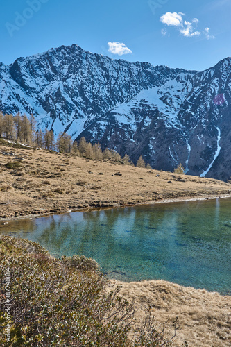 Reflecting mountain lake in front of snowy mountain peaks. Mountain landscape with reflecting lake and snowy mountains. Glacial lake in the mountains in South tyrol. Reflecting lake in the mountains.
