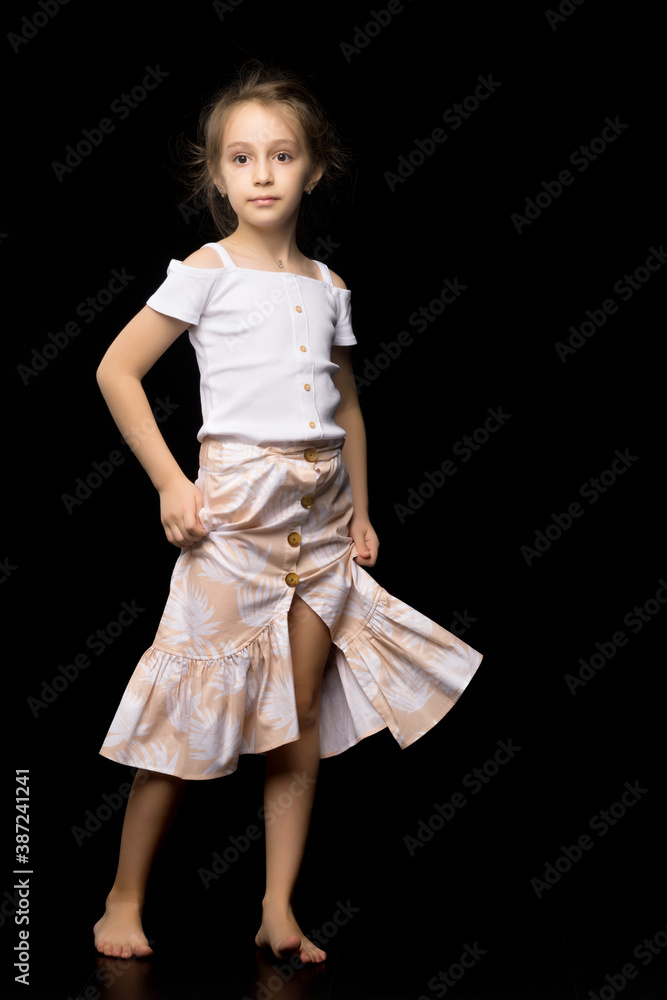 A beautiful girl stands with her head bowed, smiling at the camera, a beautiful child in stylish fashionable clothes posing on a white studio background A beautiful girl stands with her head bowed, smiling at the camera, a beautiful child in stylish fashionable clothes posing on a white studio background