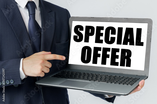 A businessman holds a laptop in his hands and shows on the screen with the text - SPECIAL OFFER