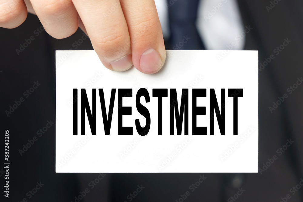 Businessman shows a card with the text INVESTMENT Businessman shows a card with the text INVESTMENT